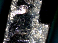 Close-up picture of the key after 5,000 uses. Large craters of material have been removed and lubricant deposited.